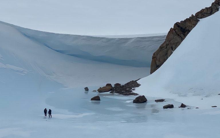 researchers in front of glacier in antarctica